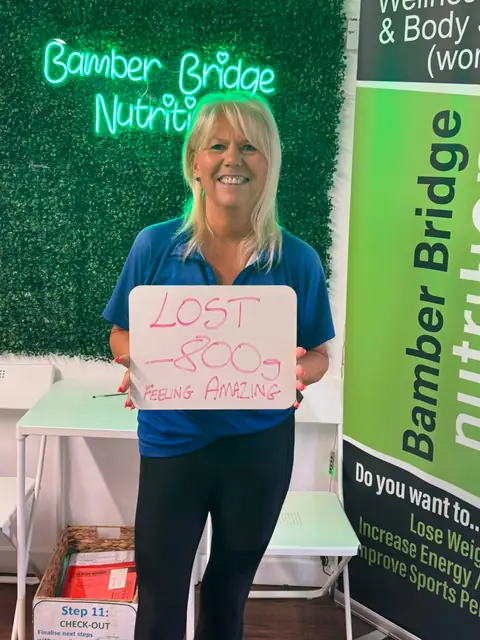 Smiling member at the club showing her results written up on the board