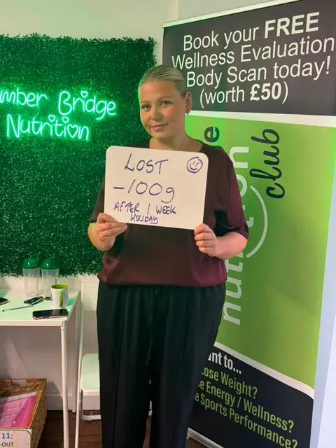 Inside the club, a member displays her assessment results on a whiteboard
