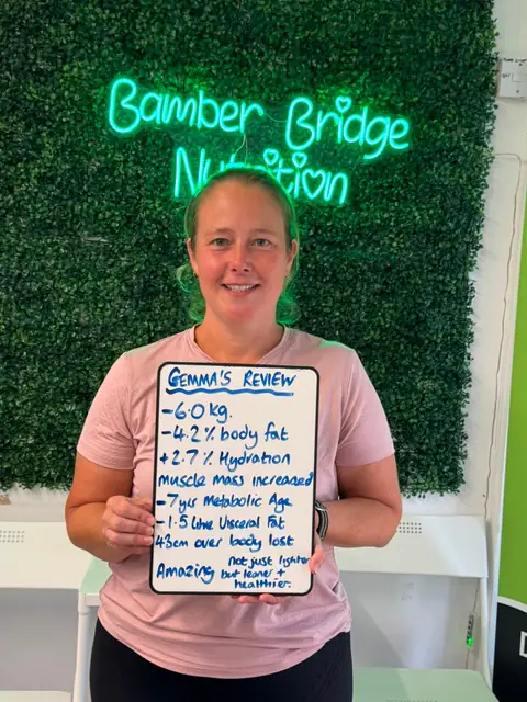 Inside the club, a member displays her assessment results on a whiteboard