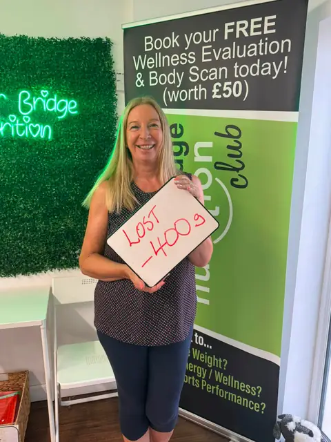 Smiling member at the club showing her results written up on the board