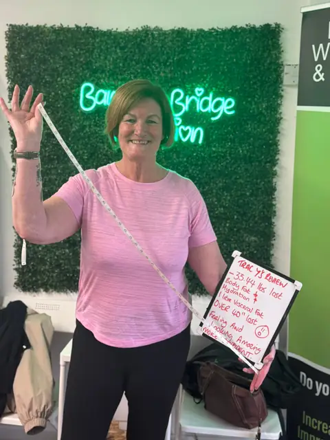 Inside the club, a member displays her assessment results on a whiteboard