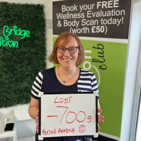 Inside the club, a member displays her assessment results on a whiteboard