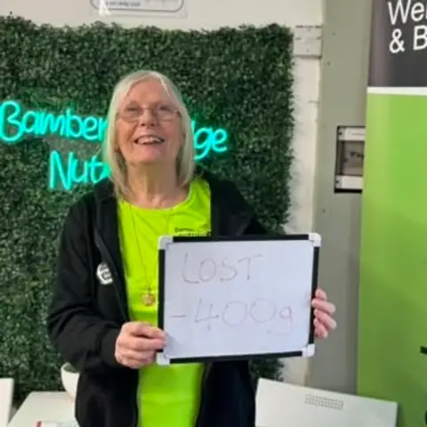 Inside the club, a member displays her assessment results on a whiteboard