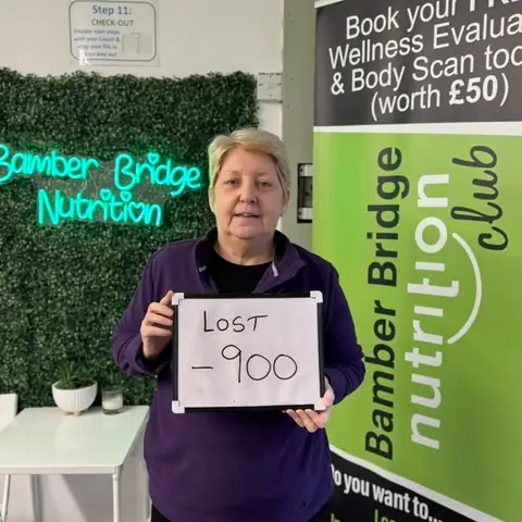 Smiling member at the club showing her results written up on the board