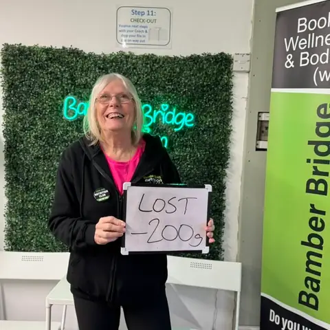 Inside the club, a member displays her assessment results on a whiteboard